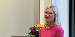 Blonde Frau steht an Stehtisch und spricht 
