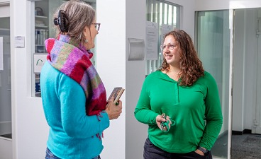 Zwei Frauen im Gespräch in einem Flur stehend