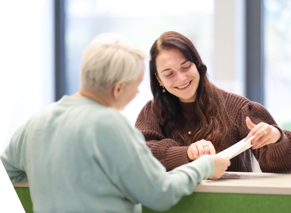 Gesprächssituation am Tresen: eine Frau berät eine andere
