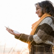 Eine Frau legerer Freizeitkleidung blickt auf ihr Smartphone.